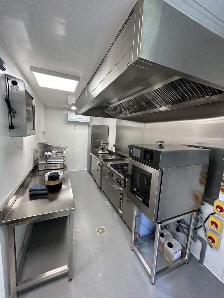 Container cuisine intérieur vue sur l'espace de cuissonn mur pvc blanc sol en résine grise le tout en longueur